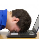 Man hitting head on laptop in frustration